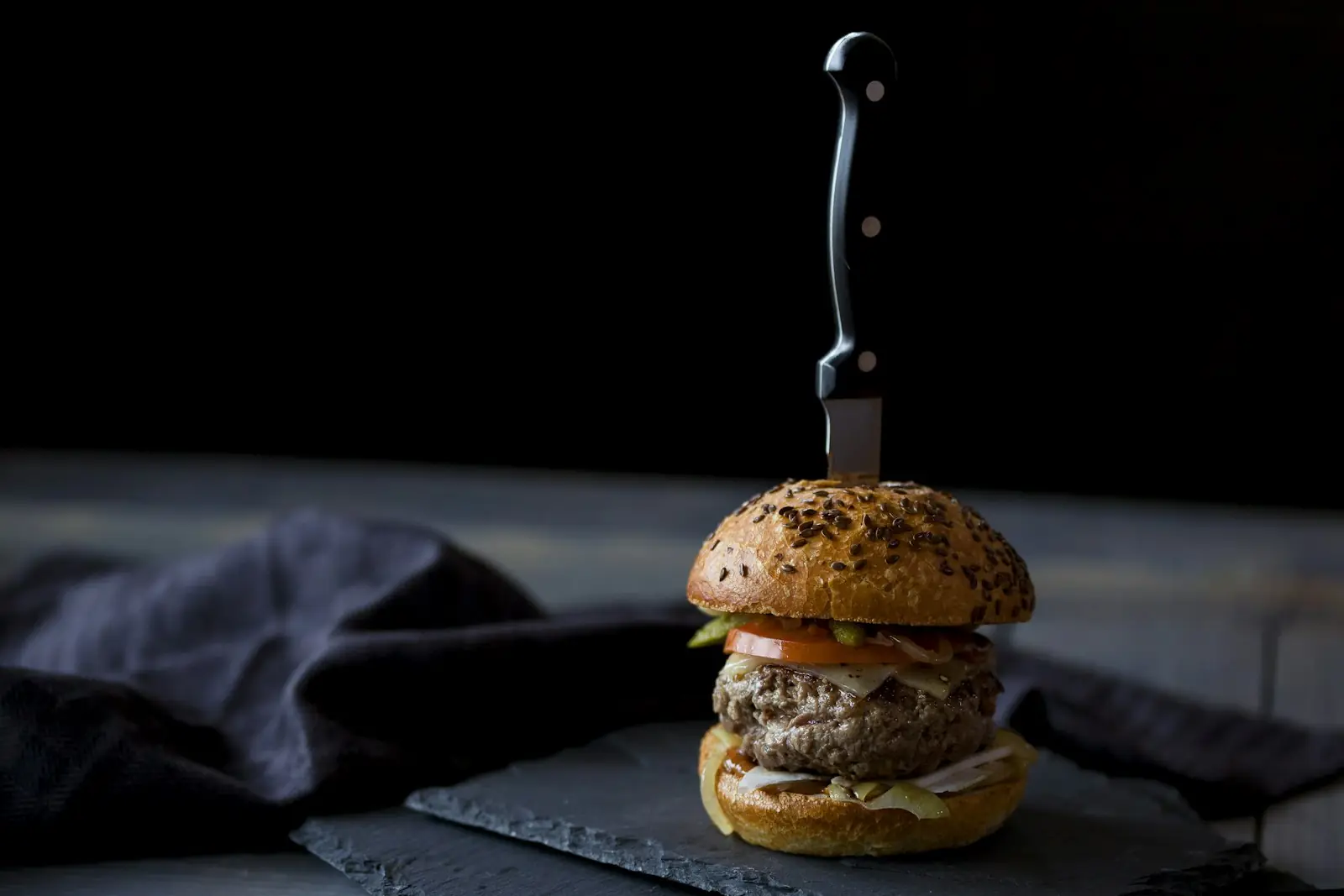 Le Minuit, burger servi au couteau sur fond noir