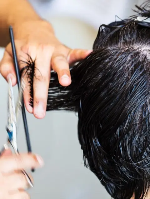 Coupe aux ciseaux sur des cheveux bruns mouillés, vue de dessus