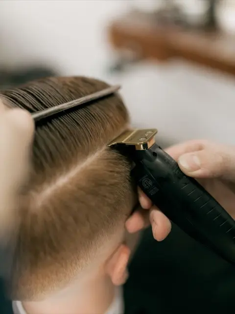 Tondeuse dorée et peigne qui dessinent un dégradé sur une nuque