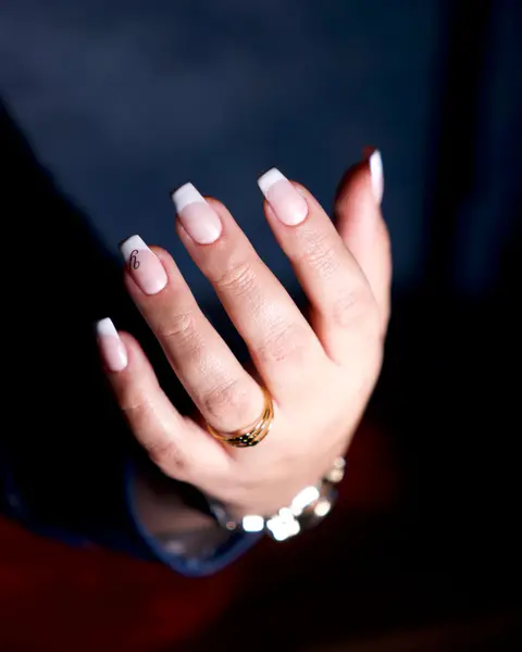 Main aux ongles longs et carrés, French blanche sur base laiteuse, sur fond bleu nuit