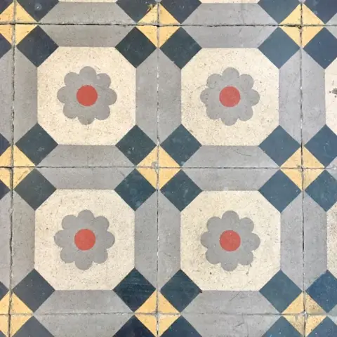 Carreaux de ciment anciens à motif octogonal gris, anthracite et ocre, avec une fleur rouge au centre
