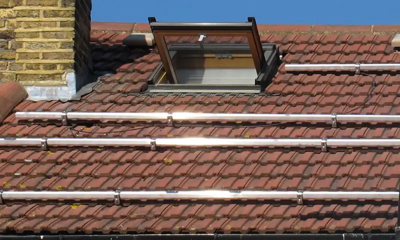 Trois rangées de rails en aluminium fixées sur une toiture en tuiles mécaniques, avant la pose des panneaux
